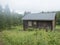 View of STF Njunjes Mountain cabin on a meadow, moody rainy day with thick fog. Wooden cottage lies on the banks of the