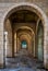 View of a stone-built covered corridor with gates and arches on a square in Tel Aviv Israel, with the contours of a surfer in the