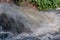 A view of the stormy flow of clear water from the culvert on a bright summer day