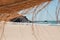 View from a straw parasol on natural lanscape of Atlantic ocean beach and group of surfers walking past sandy seaside