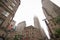 A view of a street in Downtown Manhattan. High skyscrapers rising to the sky on a cloudy weather day. New York urban streets