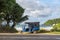 View of the street of Mirissa town with a taxi made of a moped tuk-tuk on the background of the ocean