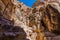 A view of sunlit jagged rock faces above the path approaching the ancient city of Petra, Jordan