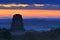 View of a sunrise above the Peten jungle with the pyramids of Tikal towering above the tree canopy in Guatemala