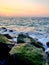 A view of the sunset extending across the sea surface to the breakwater rocks