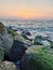 A view of the sunset extending across the sea surface to the breakwater rocks