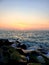 A view of the sunset extending across the sea surface to the breakwater rocks