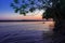 View sunset of Madre de Dios River, with trees and a boat in the water, Puerto Maldonado