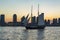 View during sunset on an old sailing ship sailing on the Hudson River and the sun setting between the sky-line of Jersey City, New