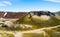 View on surreal volcanic landscape with green black volcano crater and red mountain range against blue sky