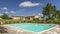 View of the swimming pool of a tourist resort surrounded by greenery in Tuscany, Italy, with movement of clouds in time lapse