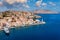 View on Symi (Simi) island harbor port, classical ship yachts, houses on island hills, Aegean Sea bay. .