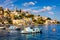 View on Symi Simi island harbor port, classical ship yachts, houses on island hills, Aegean Sea bay. Greece islands holidays