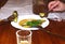 View of the table with a white plate and pickles in it, three forks. A glass in the foreground