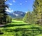 A view from the tee box looking down a tough par 4 lines with trees and the rocky mountains in the background.