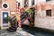 View of tiny bridge with flowers and lampposts into a typical Venice restaurant