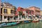 View to the channel, boats, buildings and people at the street in early spring in Murano, Italy.