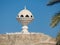 View to the Riyam Park monument dome through the palm leaves. Muscat, Oman.