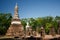 View to the ruins and sitting Buddha statue in Sukhothai Historical Park