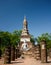 View to the ruins and sitting Buddha statue in Sukhothai Historical Park