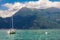 View to sailboat anchored in harbor the village of Varenna on Lake Como. Scenic landscape on background alps mountains, trees and