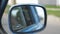 View to side mirror of old retro car with blurred city at background. Vintage automobile driving at the city street on