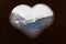 View to snowy Swiss alps in winter through wooden heart shape