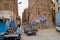 View to the street with market stall and car passing in Shibam, Yemen.