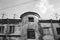 View to the top floor of an old, flaky house with a circular entrance and roof antennas. Black and white photo