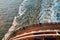 View from the top at the back deck of the cruise ship, leaving foamy trace on the water and waves in the ocean during sunset.