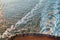 View from the top at the back deck of the cruise ship, leaving foamy trace on the water and waves in the ocean during sunset.