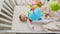 View from top on cute 3 months old baby lying in crib and looking at spinning colorful toy carousel
