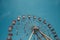 A view of the top half of a vintage Ferris Wheel fairground ride with blue sky background and copy space