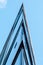 View at top of modern office building with glass and steel under blue sky, reflections and selective focus.