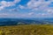 View from the top of the mountain on the boundless expanses of mountains and hills of green Carpathians with blue sky