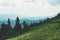 View from top mountain to wooded mountain landscape against background sky covered white-gray dense clouds.