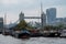 View of Tower Bridge and tall City buildings in the background. In the foreground are houseboats at Shad Thames.
