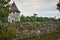 View of the tower of Chateau de la Brede castle behind a stone wall