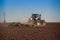 View of tractor seeder sowing in ploughed field