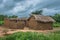 View of traditional village, house thatched on roof and terracotta walls, dramatic cloudy sky as background