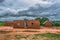 View of traditional village, thatched houses with roof and terracotta brick walls, cloudy sky as background