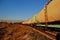 View of the train of cisterns and wagons at sunrise against the blue sky.