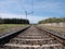 View from the train tracks towards an infinite straight between sleepers and the ballast under the wires of the catenary