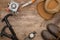 View of trekking poles, gas burner, jackknife, hat, boots and compass on wooden table