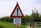 View on triangular warning sign on apple fruit tree plantation. German text means: autonomous driving tractor