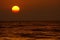 View on tropical sunset with big round sun over ocean horizon, dark shimmering water - Sri Lanka