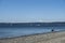 View of two people walking along the beach at Discovery Park, with the Olympic Mountains in the background