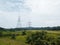 View of two powerline towers standing on a green meadow on a gloomy day background