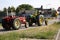 View on two vintage tractors waiting at closed railway crossing barriers