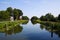 View on typical dutch endless straight waterway canal lined with green grass and trees in countryside